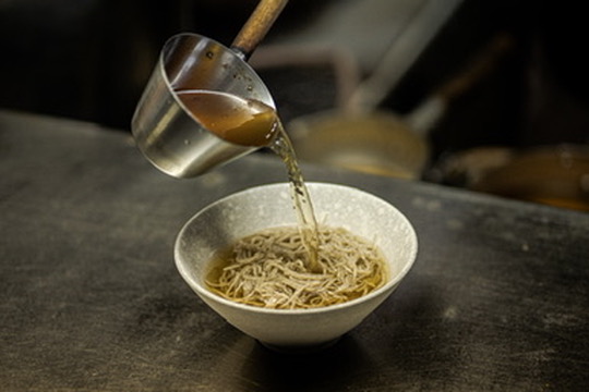 そばに関西風出汁を注ぐ様子